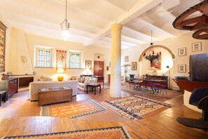 A spacious living area with a sofa, coffee table, and rugs, a dining area with chairs, and a large pillar. - Villa Roocello, charming restored olive mill, with (Capannori)