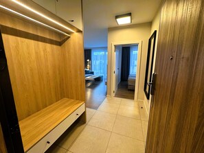 Ein Hotelgang mit einer hölzernen Bank, einem Bett und einem Badezimmer mit Spiegel.
