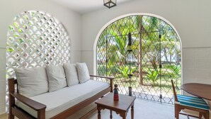 A room with a white sofa, a small wooden table, and a dining table with chairs. - Watano Beach House Spacious 7-bedroom house in awesome Diani perfect for groups (Diani)