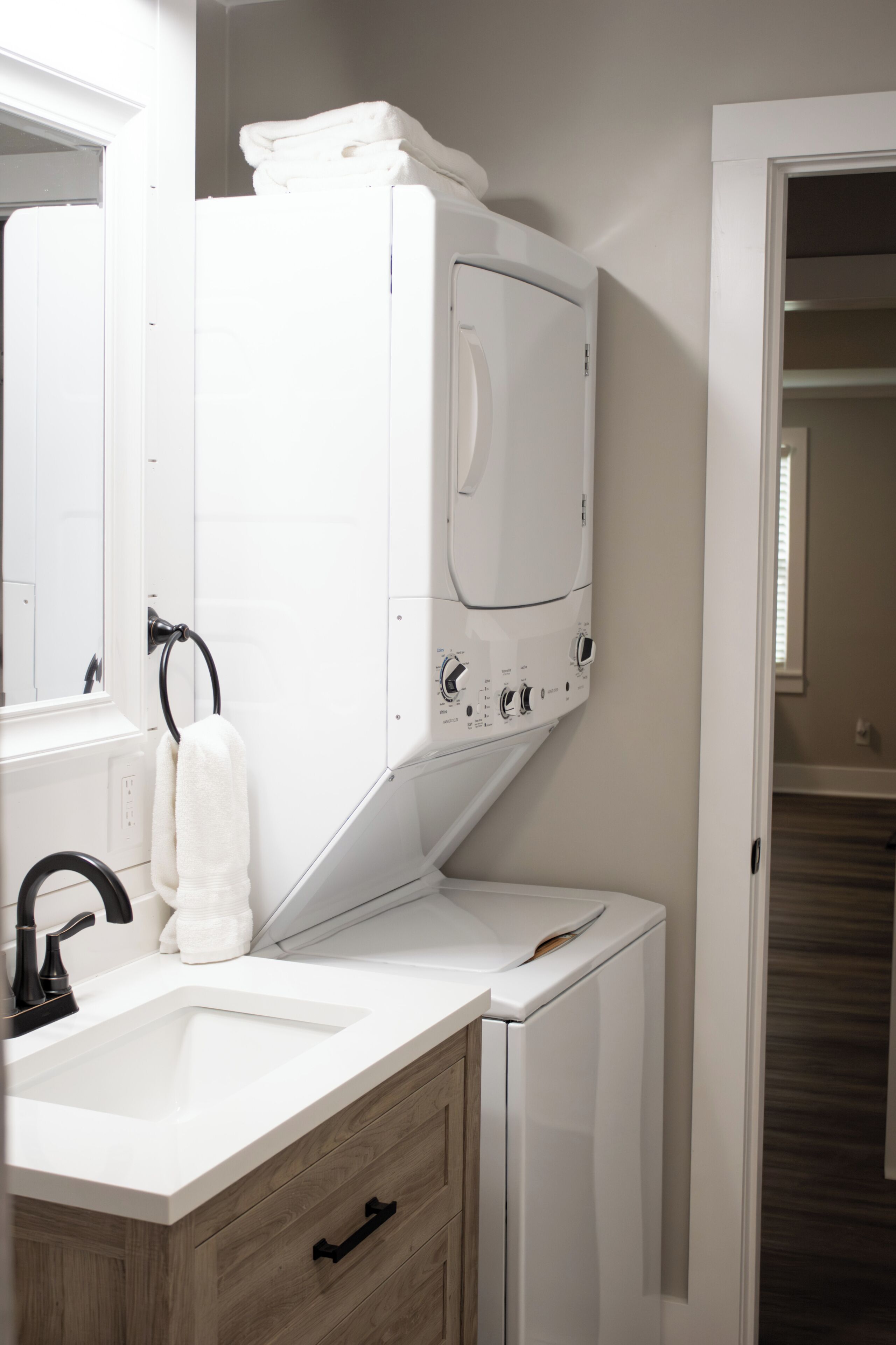 Une petite salle de bain avec un lavabo blanc, un miroir, un porte-serviettes et un lave-linge blanc.