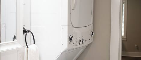 Une petite salle de bain avec un lavabo blanc, un miroir, un porte-serviettes et un lave-linge blanc.