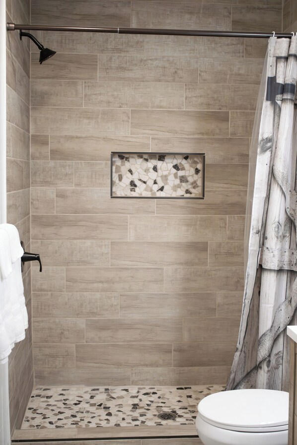 A shower with a tiled wall, a framed artwork, and a curtain.