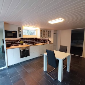A modern kitchen with white cabinets, a black microwave, and a window above the sink.