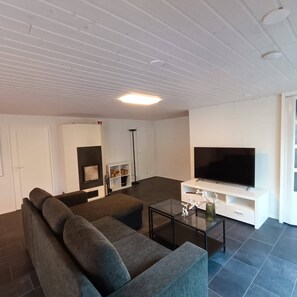 A modern living room with a sectional sofa, a flat-screen TV, and a glass coffee table. - Spacious Luxury Apartment (Hameenlinna)