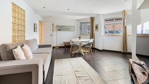 Een moderne woonkamer met een bank, eettafel en een groot raam.