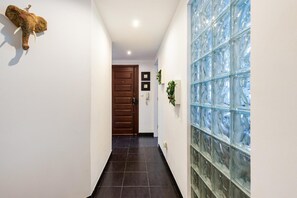Un couloir avec une porte en bois, un mur en verre orné d’un motif et une sculpture d’éléphant fixée au mur.