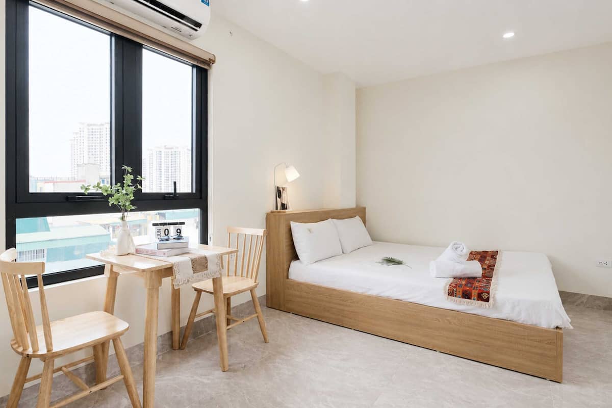 A minimalist bedroom with a bed, a desk, and chairs.