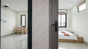 Une chambre d’hôtel moderne, équipée d’un lit, d’un bureau et d’une chaise, et offrant une vue sur l’extérieur.