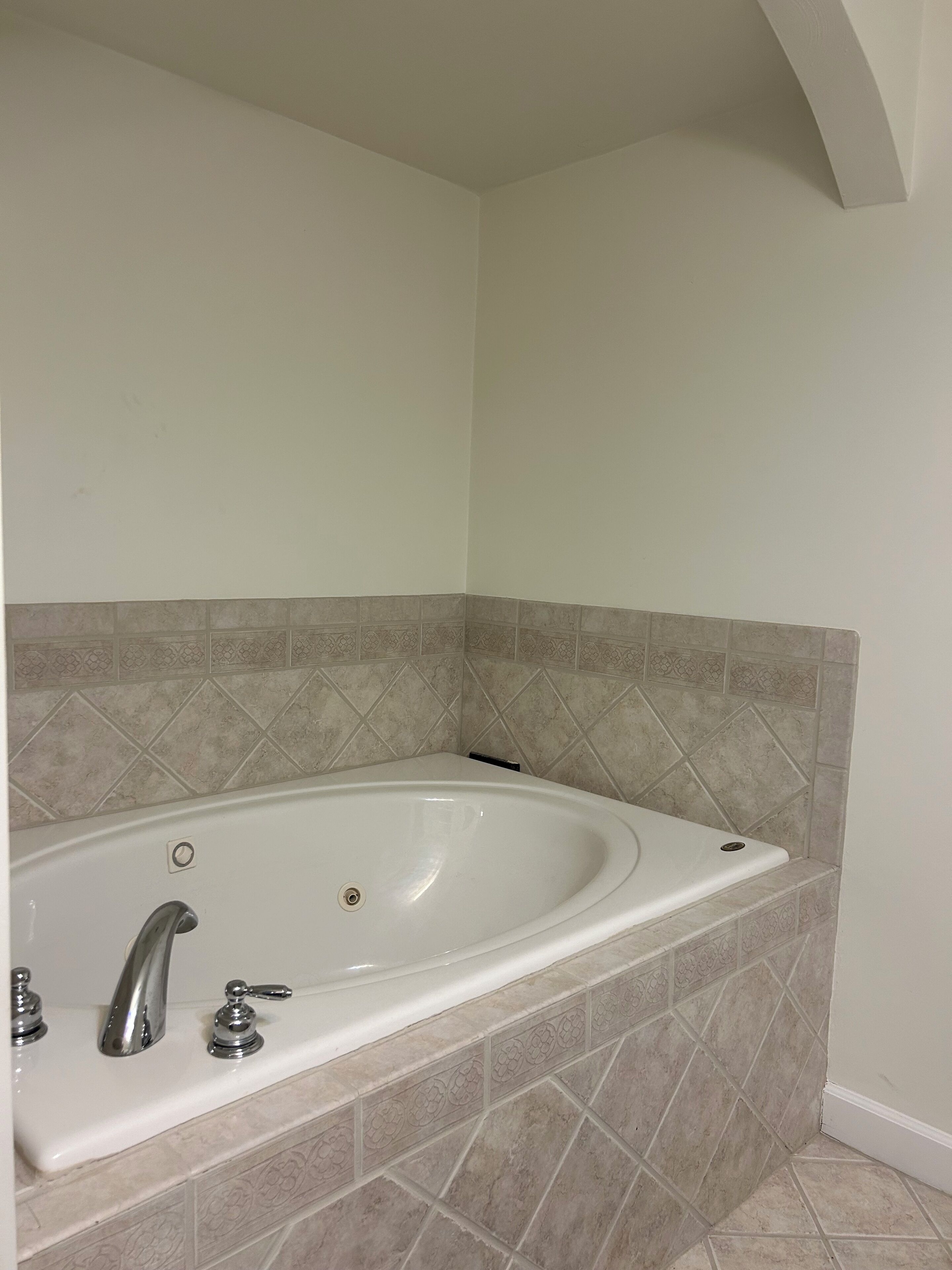A bathroom with a freestanding bathtub, a wall-mounted faucet, and a tiled floor.