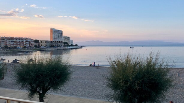 Ein Hotel an der Küste mit Blick auf den Strand, ein Gewässer und eine ferne Bergkette.