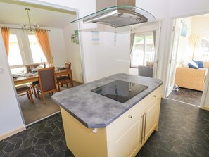 Una cocina moderna con una isla central, un comedor con mesa y sillas, y vistas al exterior.