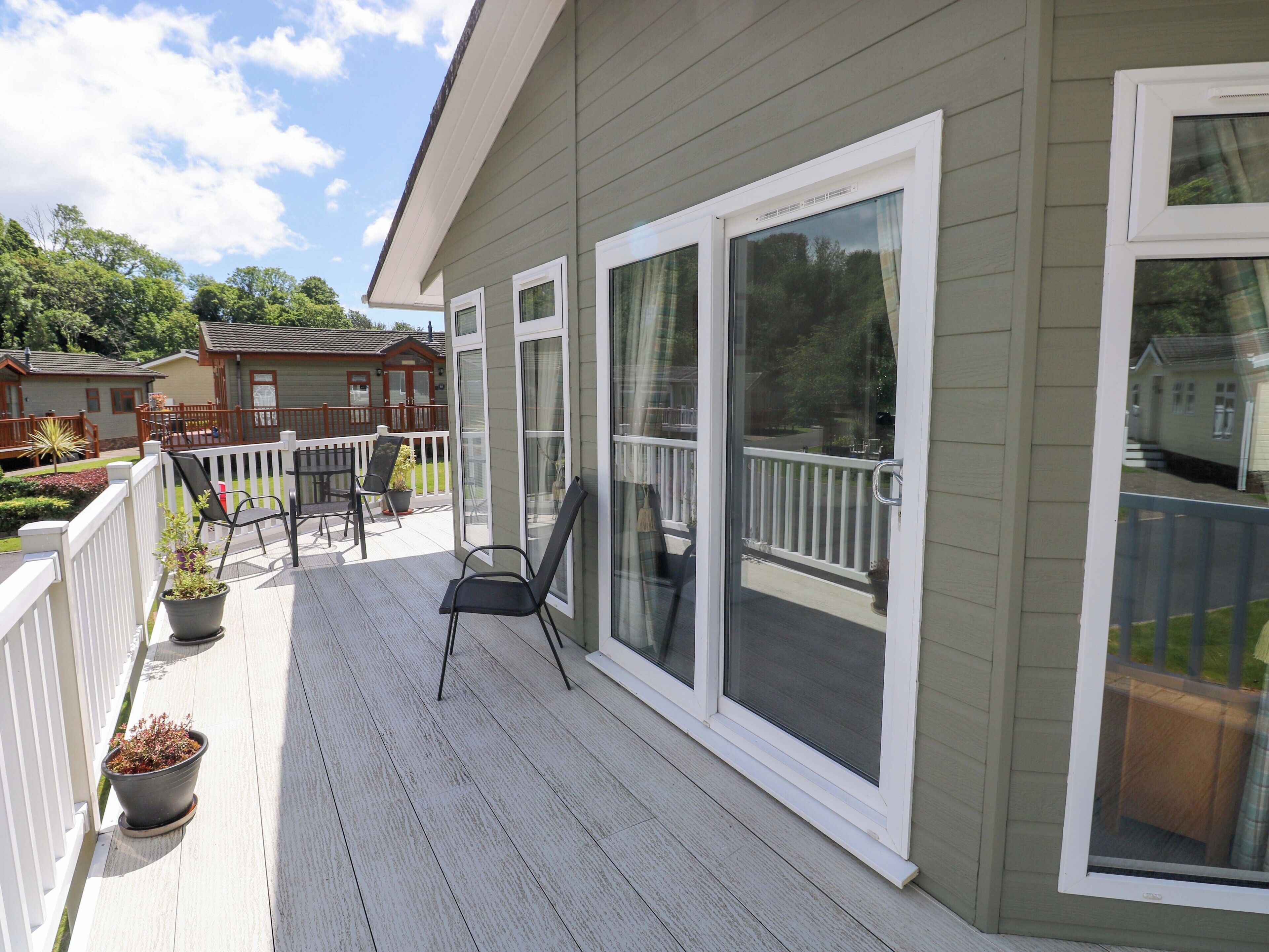 A covered deck with a railing, a chair, and a potted plant.