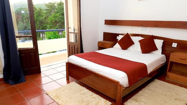 A bedroom with a wooden bed, white bedding, and a view through a glass door. - Braga Restaurante e Residencial (Lourinha)