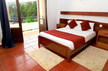 A bedroom with a wooden bed, white bedding, and a view through a glass door.. Braga Restaurante e Residencial