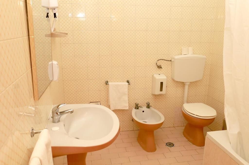 A bathroom with a sink, bidet, toilet, and a mirror.
