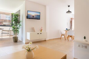 Ein modernes Wohnzimmer mit Fernseher, Essbereich und einer Pflanze.
