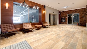 A reception area with a wooden wall, a large window, a reception desk, and a waiting area with chairs. - Live & Travel Apartments Waterlane  (Gdańsk)
