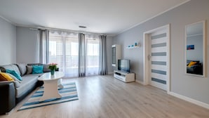 A modern living room with a sofa, TV, and a coffee table. - Live & Travel Apartments Waterlane  (Gdańsk)