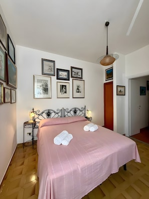 A neatly made bed with a pink bedspread, two rolled towels, and a wall adorned with framed pictures. - Bed and Breakfast 'La Camera Delle Ragazze' with Shared Pool, Wi-Fi, and Air Conditioning (Polignano a Mare)
