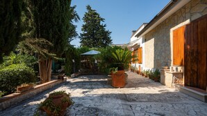 A courtyard with stone flooring, potted plants, a wooden door, and a stone wall. - Bed and Breakfast 'La Camera Delle Ragazze' with Shared Pool, Wi-Fi, and Air Conditioning (Polignano a Mare)