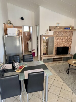 Ein stilvolles Wohnzimmer mit Esstisch, Stühlen, Fernseher und Kamin.