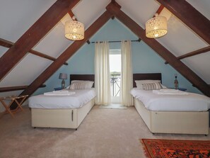 Ein Zimmer mit zwei Betten, einem kleinen Tisch, einem Stuhl und Blick durch ein Fenster.