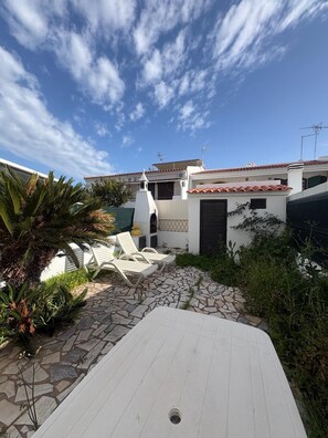A patio area with stone flooring, white lounge chairs, and a small white table. - Villa Praia (Altura)