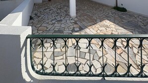 Um edifício branco com pátio ladrilhado, varanda e chão de pedra.