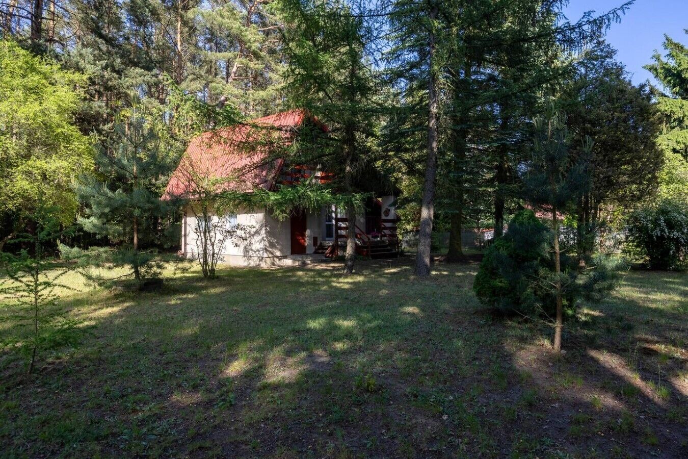Ett litet hus med ett rött tak, omgivet av träd.