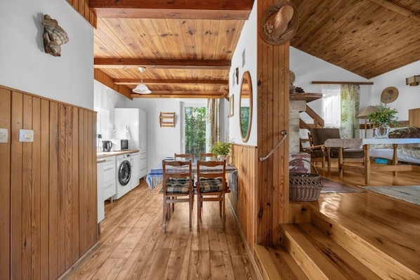 A wooden interior with a dining area, kitchen, and staircase.