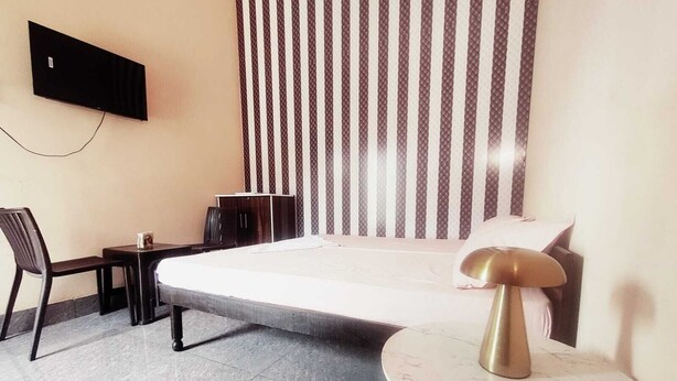 Habitación de hotel con cama, escritorio, silla, mesita pequeña, televisión montada en la pared y cortina estampada.