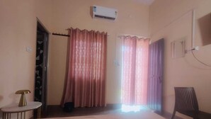 Una habitación con cama, una silla, aire acondicionado y cortinas.