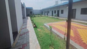 Un patio con un sendero empedrado, zona verde y un edificio de techo plano y varias ventanas.