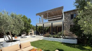 Una casa con porche cubierto, mobiliario exterior y césped bien cuidado.