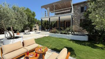 Une maison dotée d’un patio couvert, de meubles d’extérieur et d’une pelouse bien entretenue.