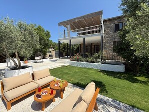 Una casa con porche cubierto, mobiliario exterior y césped bien cuidado.