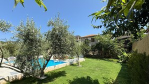 Un patio trasero con piscina, una casa de piedra y un césped bien cuidado.