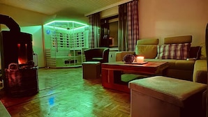 A cozy living room with a fireplace, a sofa, a coffee table, and a TV. - Eifelsuiten First Floor - Das Nest (Wiesbaum)