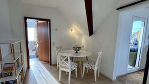 A dining area with a table and chairs, a bookshelf, and a door leading to an outdoor area. - Eifelsuiten First Floor - Das Nest (Wiesbaum)