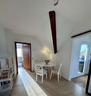 A dining area with a table and chairs, a bookshelf, and a door leading to an outdoor area. - Eifelsuiten First Floor - Das Nest (Wiesbaum)