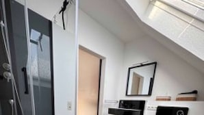 A modern bathroom with a glass shower enclosure, a toilet, and a sink. - Eifelsuiten First Floor - Das Nest (Wiesbaum)