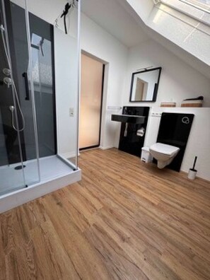 A modern bathroom with a glass shower enclosure, a toilet, and a sink. - Eifelsuiten First Floor - Das Nest (Wiesbaum)