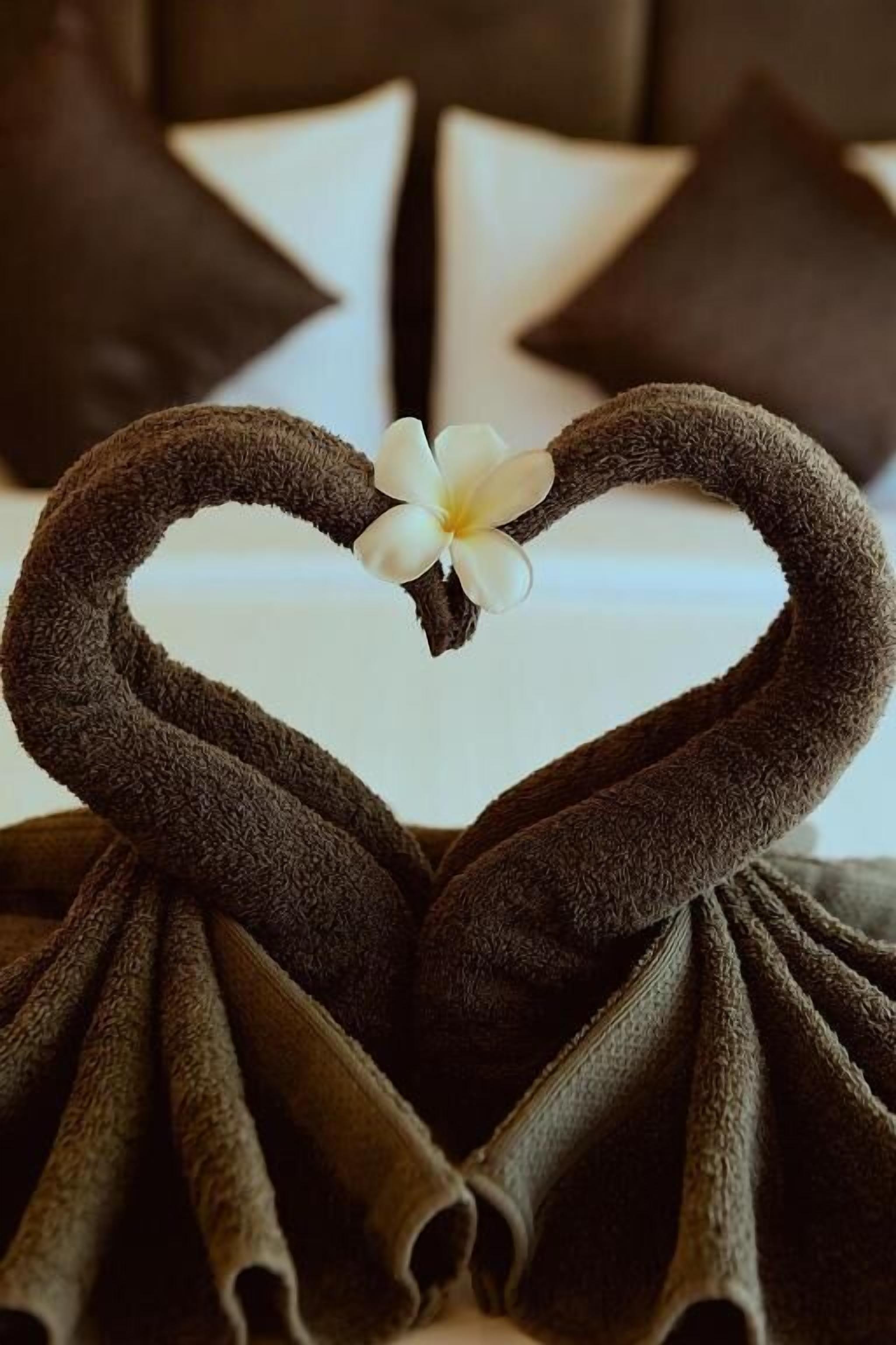 Una toalla dispuesta en forma de corazón con una flor.