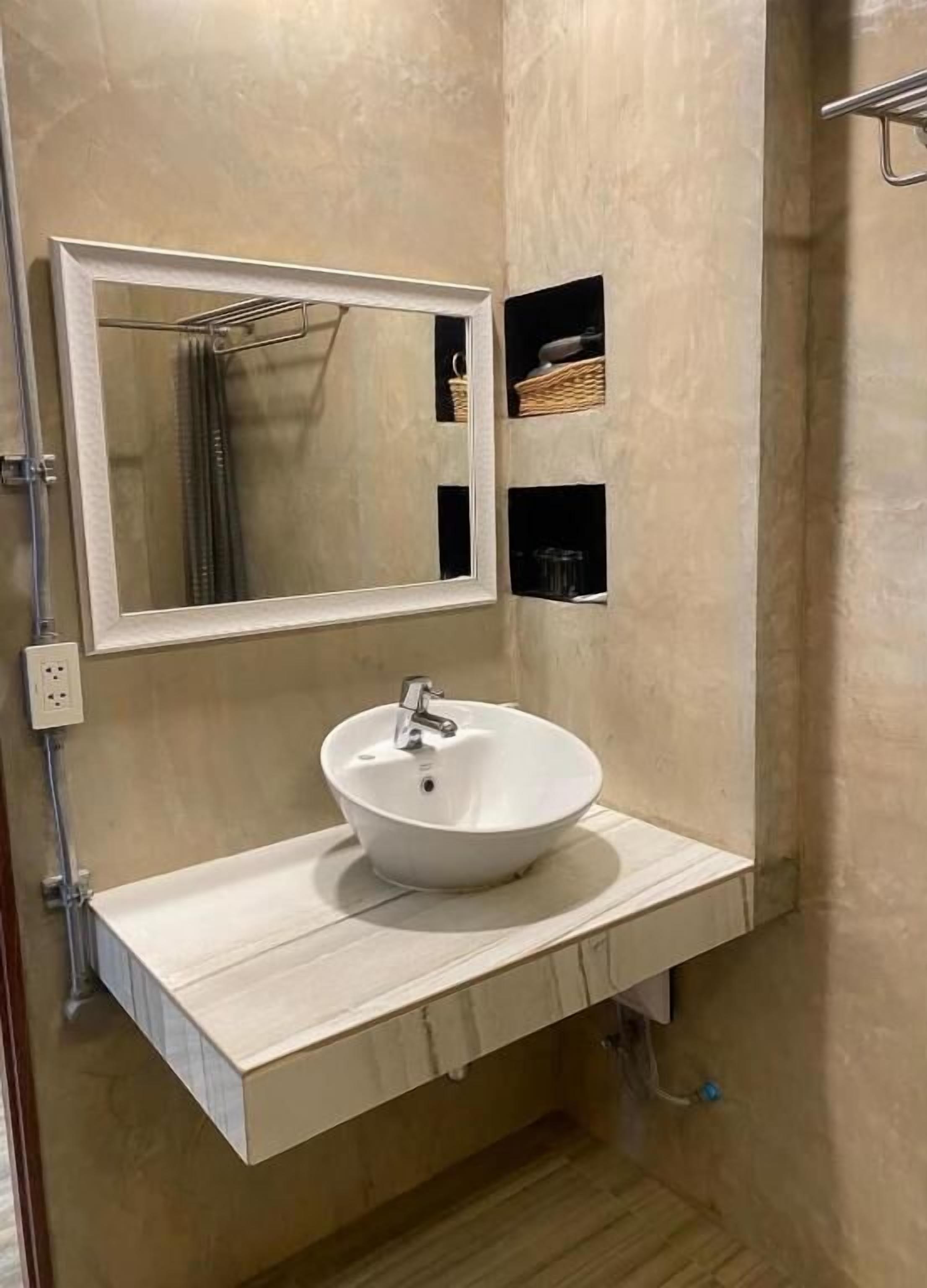 Un baño con un lavamanos blanco, un espejo y un perchero para toallas.