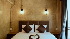 Quarto de hotel com uma cama, duas luzes fixadas na parede e uma janela com cortinas.