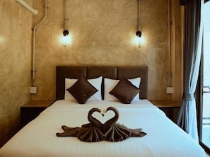 Una habitación de hotel con una cama, dos lámparas de pared y un ventanal con cortinas.