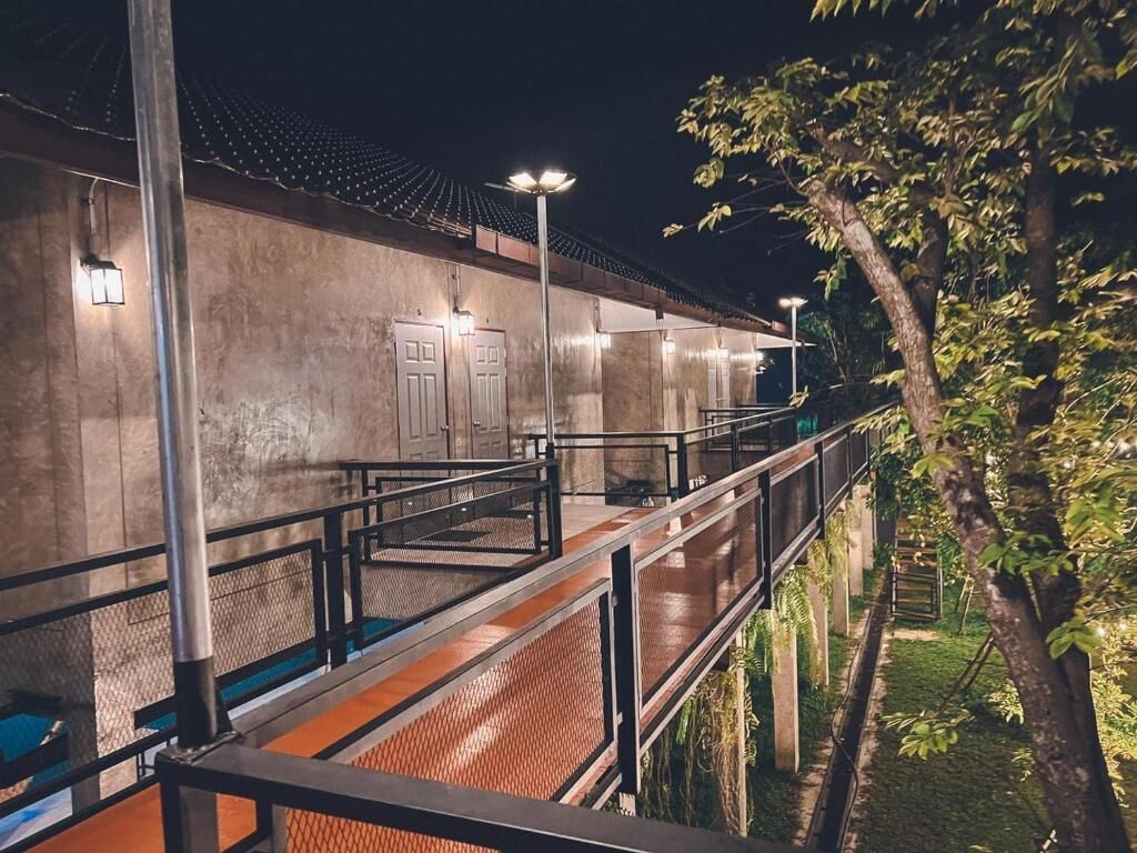 A building with a concrete facade, a covered walkway, and a tree in the foreground.