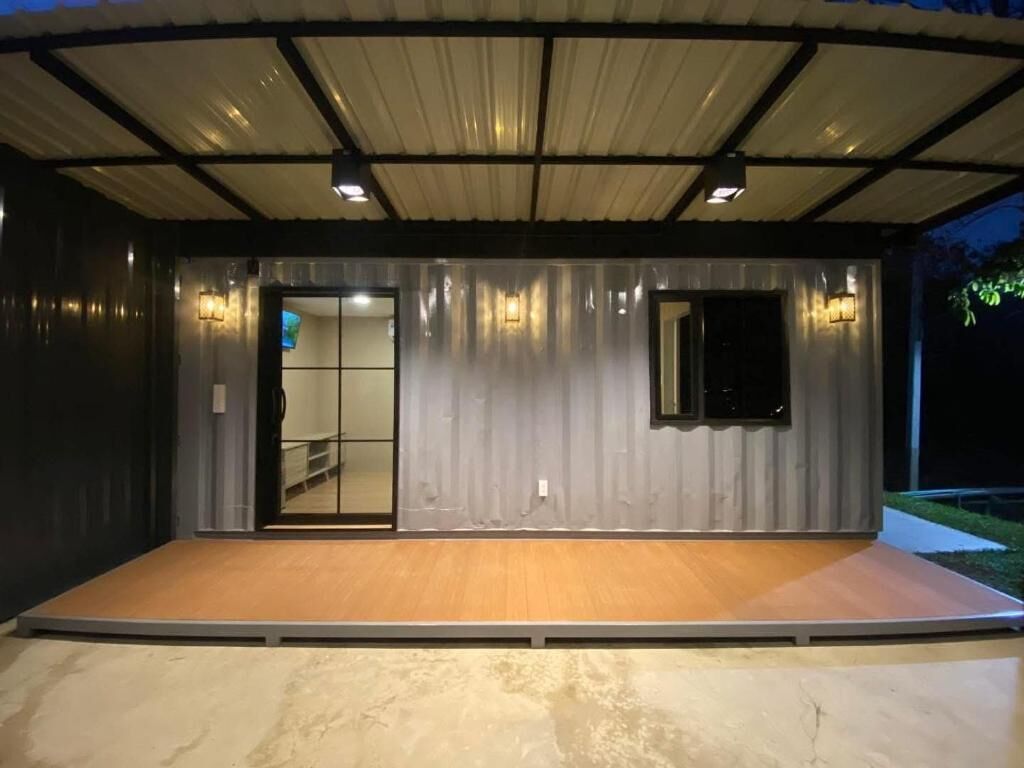 Un espacio al aire libre techado con escenario, paredes metálicas y una puerta.