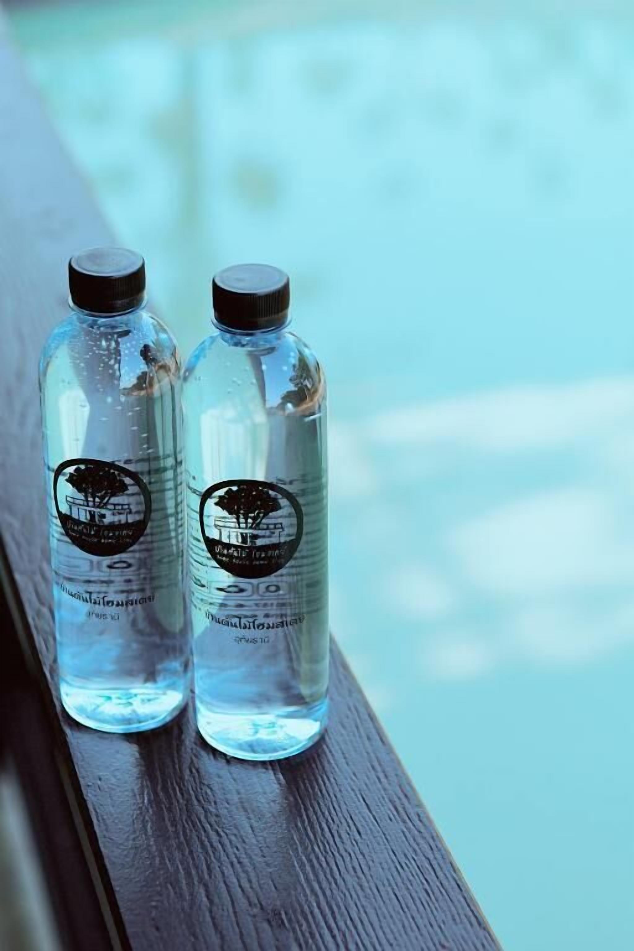Deux bouteilles d’eau transparentes, portant des étiquettes, sont posées sur une surface en bois.