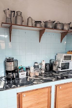 A kitchen with a coffee maker, a microwave, and various pots and pans on shelves. - Finca Luz de Palmera by Interhome (Santa Lucia de Tirajana)
